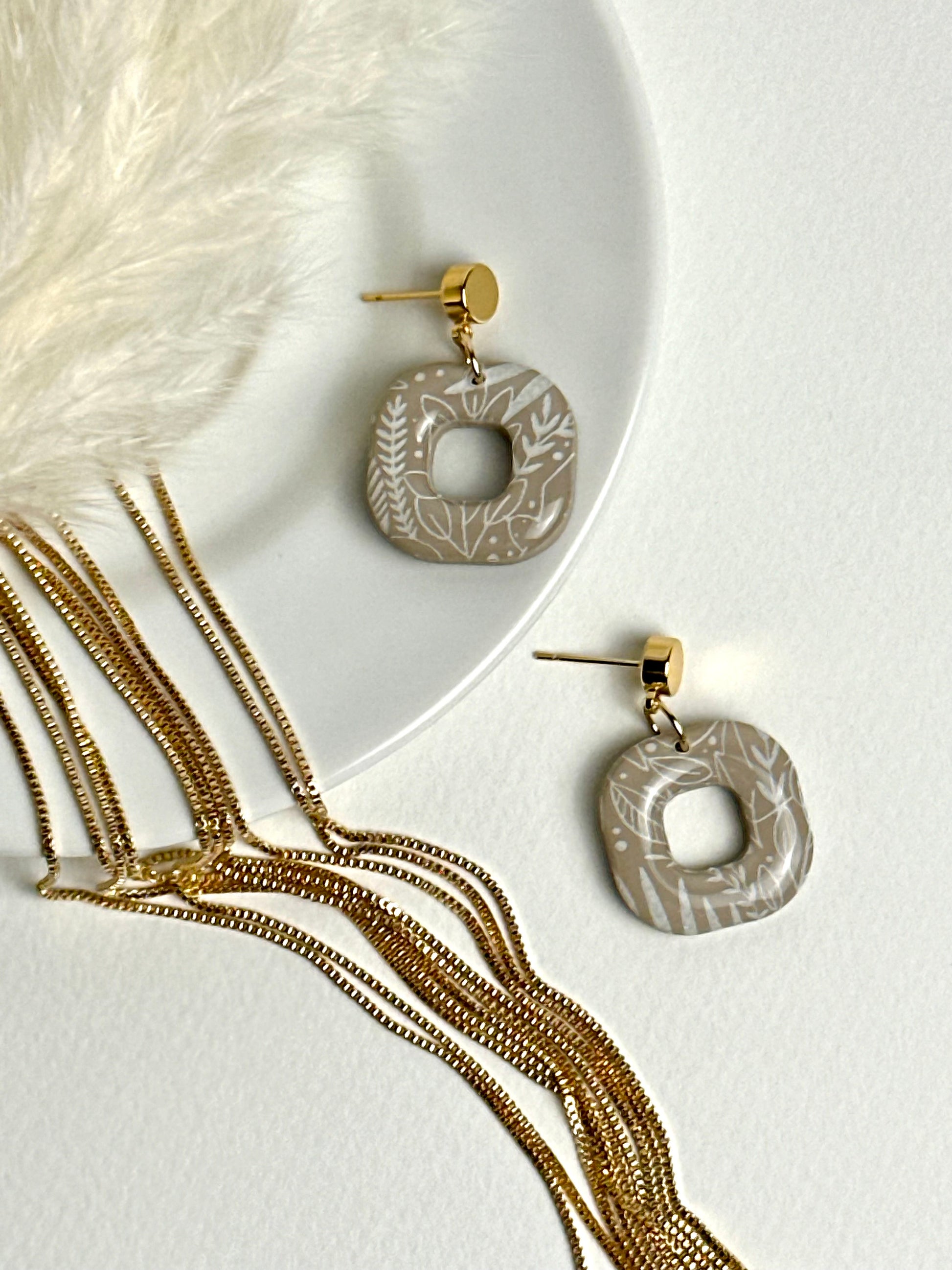 Willow earrings: handmade polymer clay squares in ash brown, with delicate white leaves dancing across the surface, gold plated posts, capturing the gentle movement of a soft breeze.