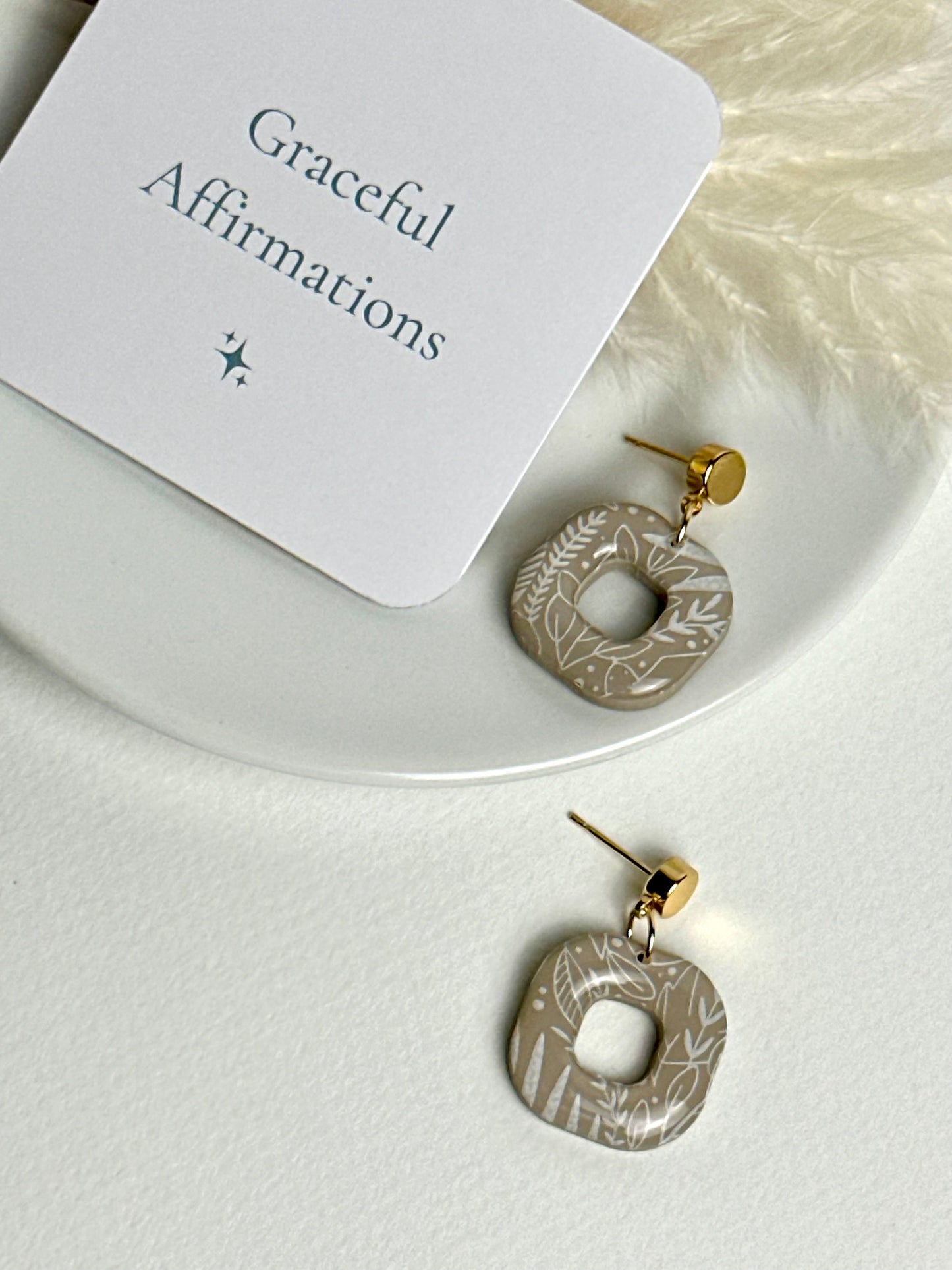 Willow earrings: handmade polymer clay squares in ash brown, with delicate white leaves dancing across the surface, gold plated posts, capturing the gentle movement of a soft breeze.