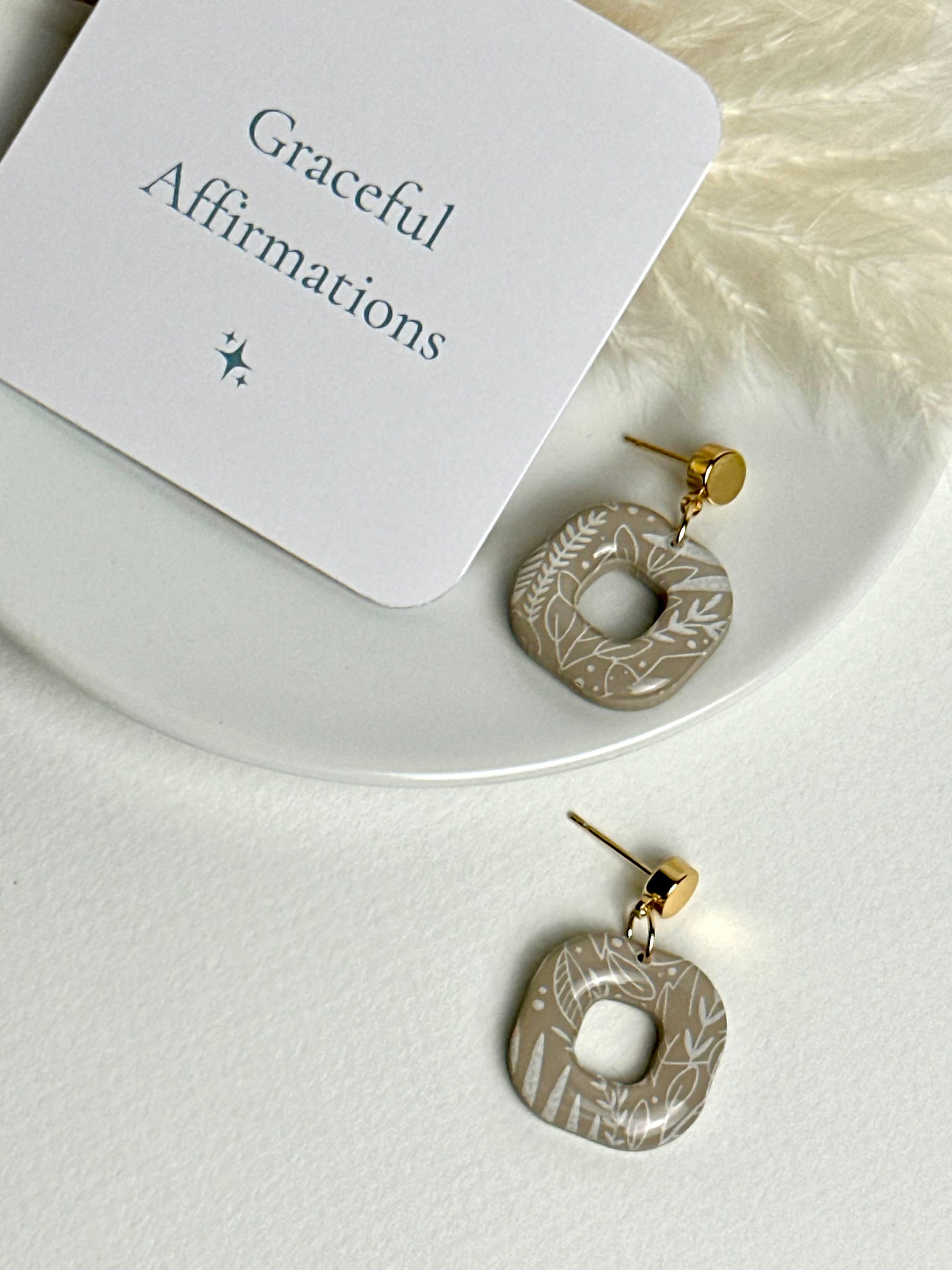 Willow earrings: handmade polymer clay squares in ash brown, with delicate white leaves dancing across the surface, gold plated posts, capturing the gentle movement of a soft breeze.