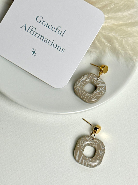 Willow earrings: handmade polymer clay squares in ash brown, with delicate white leaves dancing across the surface, gold plated posts, capturing the gentle movement of a soft breeze.