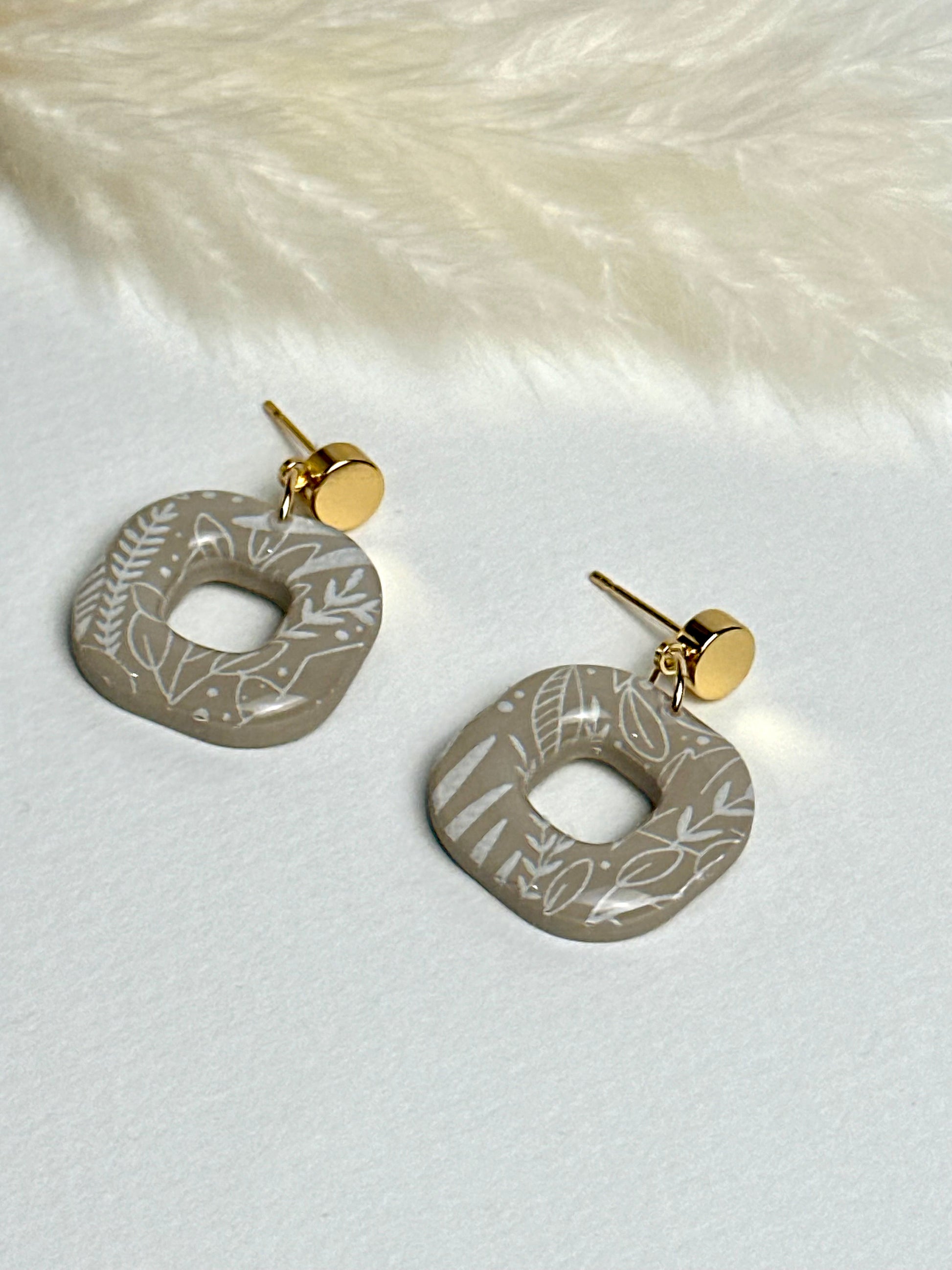 Willow earrings: handmade polymer clay squares in ash brown, with delicate white leaves dancing across the surface, gold plated posts, capturing the gentle movement of a soft breeze.