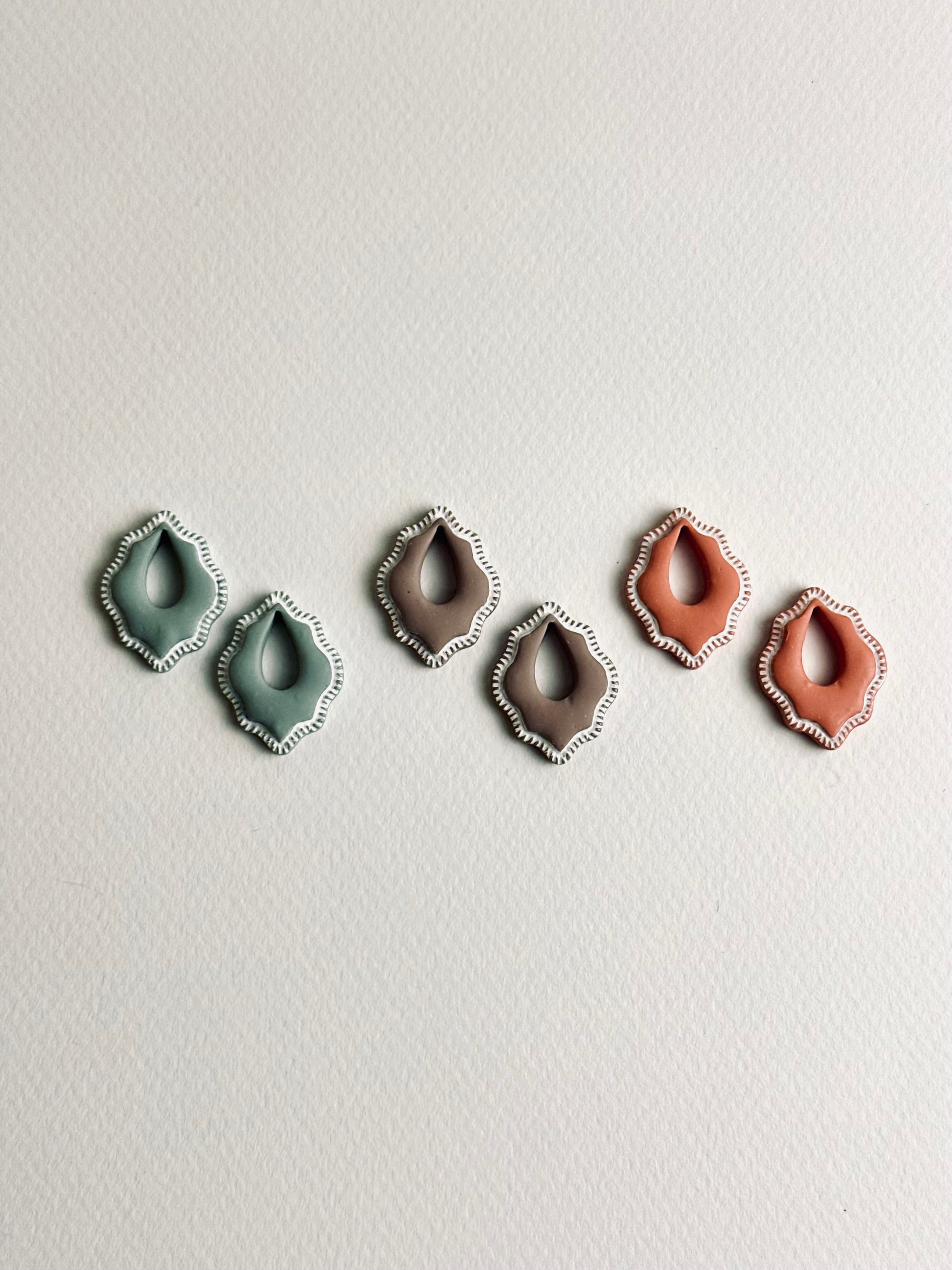 Three Valeria polymer clay charms in cocoa, soft terra, and sage mist, displayed on Versilana hoops in gold and silver tones — elegant, minimalist earrings with soft earthy colors.