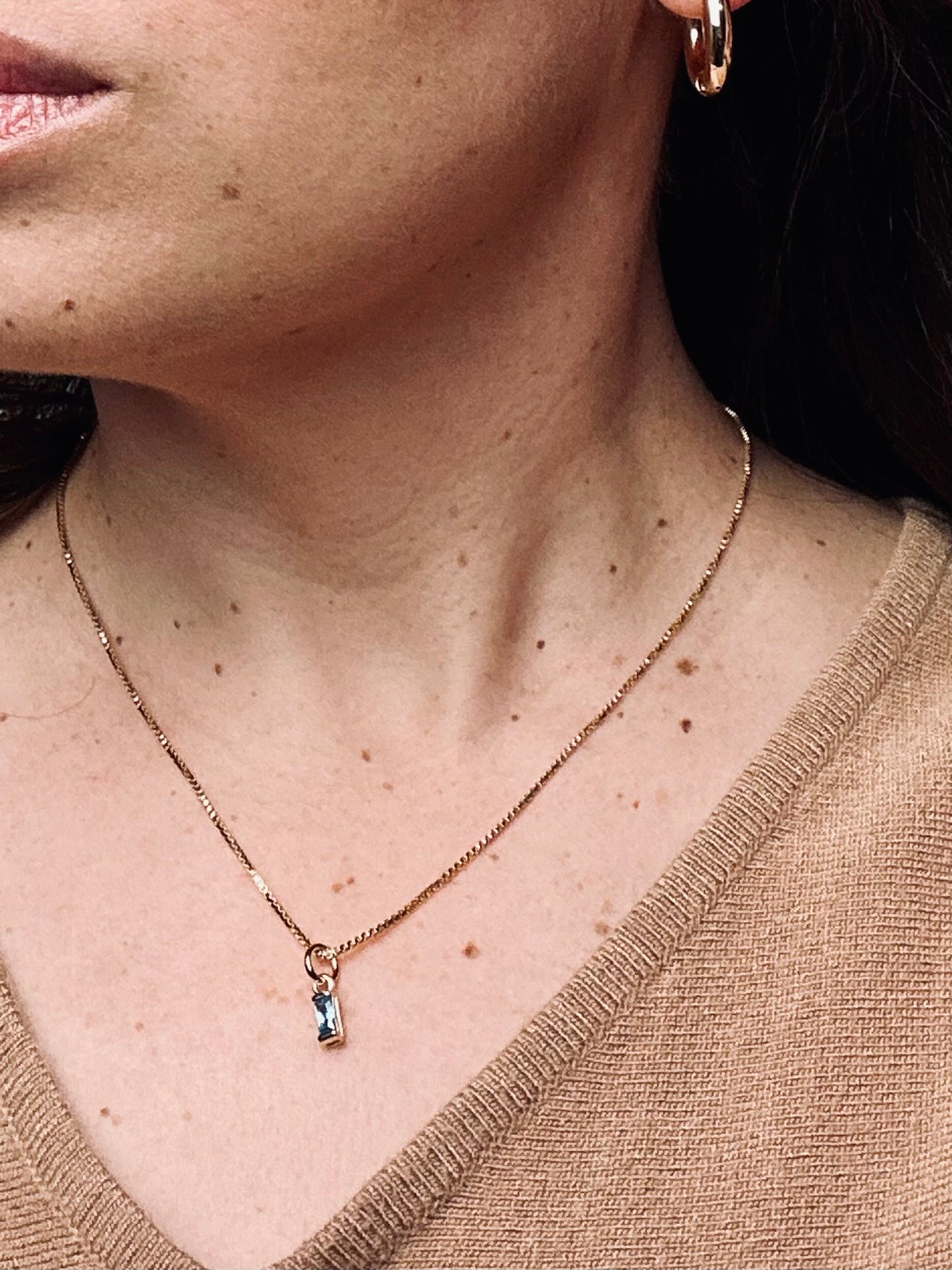 Birthstone necklace with a single stone worn by a model, paired with gold hoop earrings. The delicate 18k gold-filled box chain and shimmering gemstone create an elegant, personal look that radiates meaning and timeless grace.