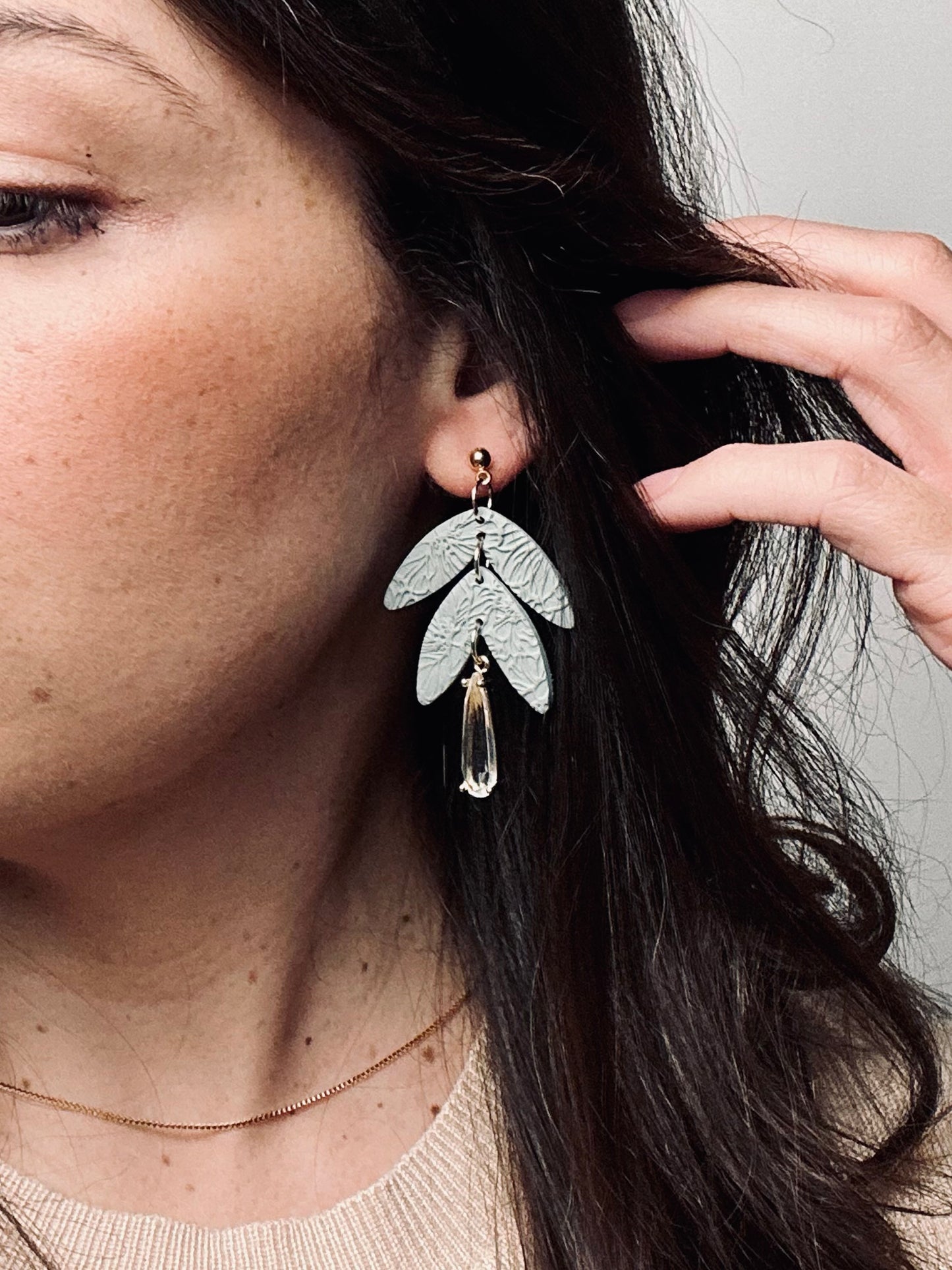 Handmade polymer clay dangle earring with rolled rose texture and a large teardrop crystal accent, elegant and feminine design.