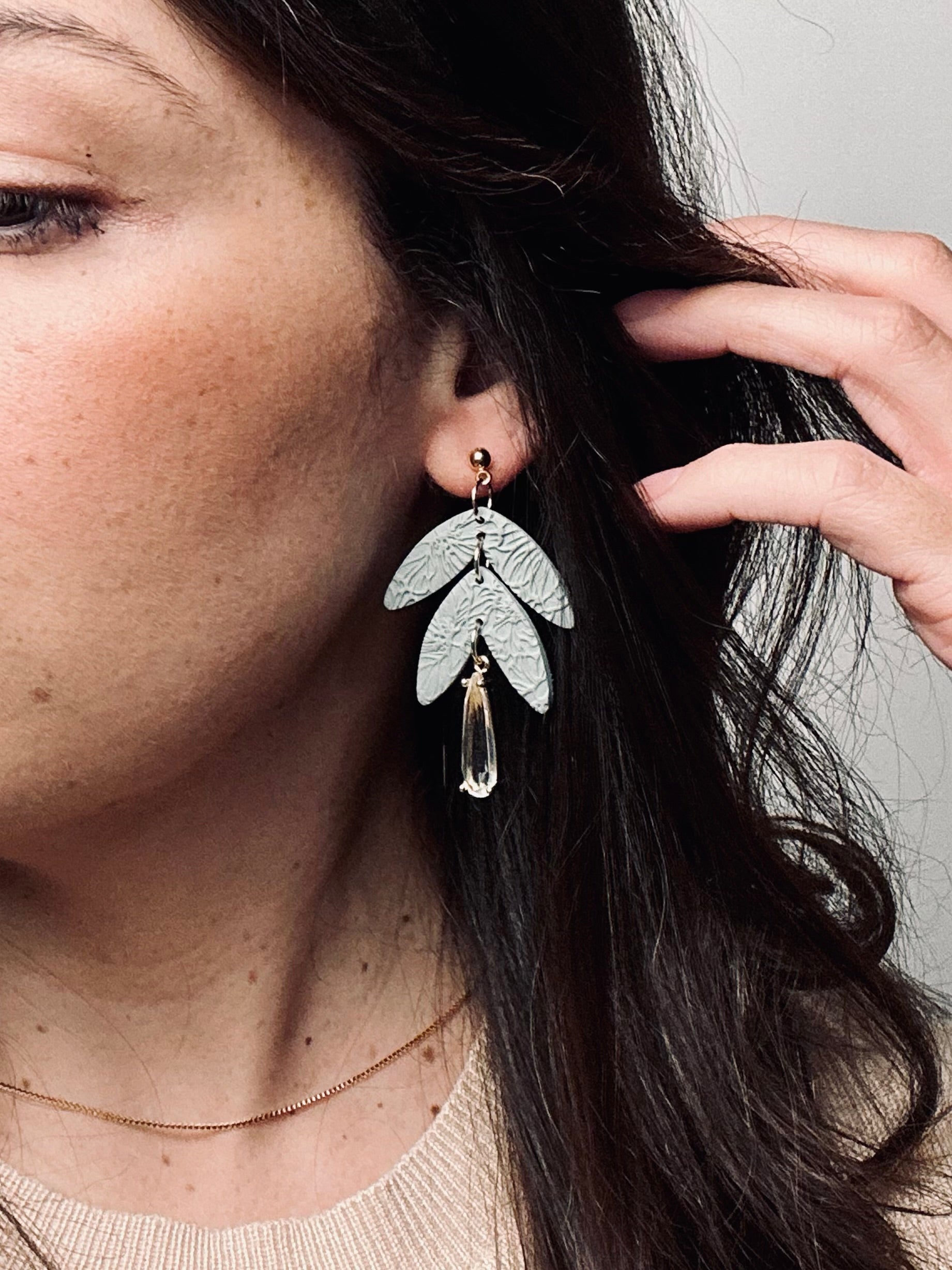 Handmade polymer clay dangle earring with rolled rose texture and a large teardrop crystal accent, elegant and feminine design.