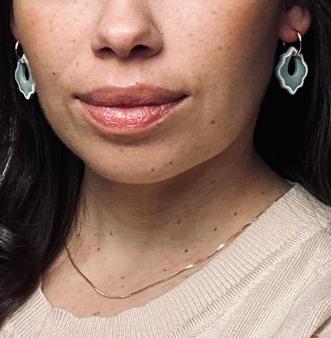 Model wearing Claylana Versilana charms on gold thin earrings.