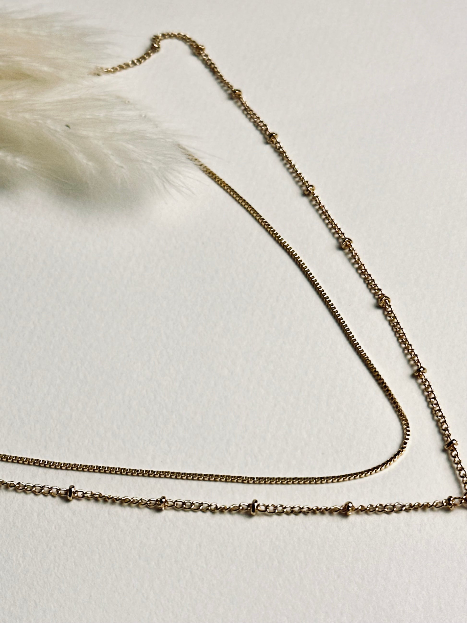 Serena — Gold Box Chain Necklace from the Timeless Grace collection, layered with another delicate gold necklace on a model. The thin gold-plated brass chains create a graceful, sophisticated look, showcasing versatile styling while symbolizing balance, elegance, and subtle self-expression.