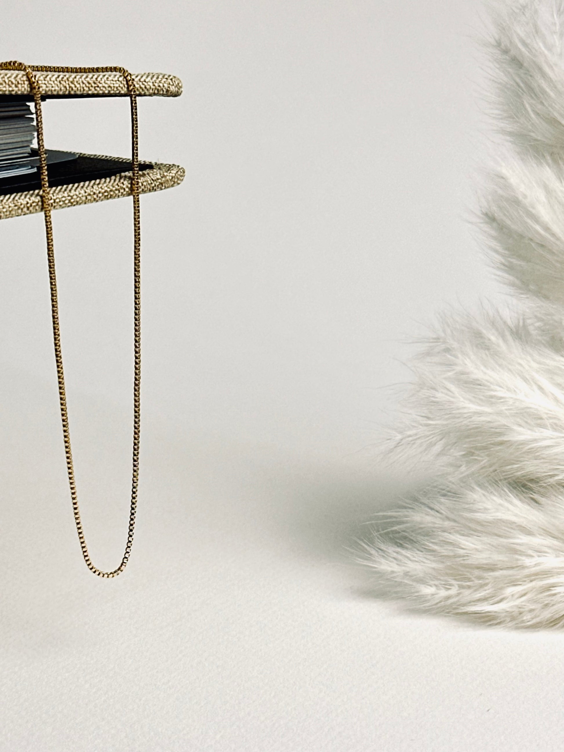 Serena — Gold Box Chain Necklace from the Timeless Grace collection, a thin gold-plated brass chain delicately draped across an open book. The soft light highlights its fine, box-style links, creating a serene and elegant mood — a gentle reminder to pause, breathe, and embrace your quiet strength.