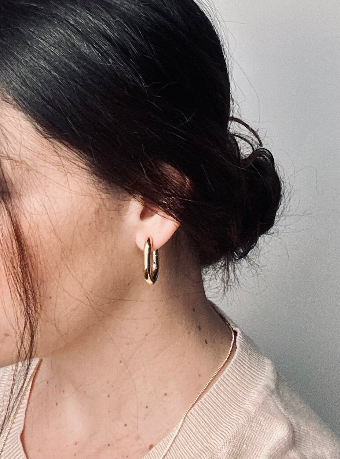 The Vera Hoop earrings worn by a model, their chunky 18k gold-plated design catching the light with a soft glow. The timeless hoops frame the face beautifully, expressing confidence, elegance, and enduring grace.
