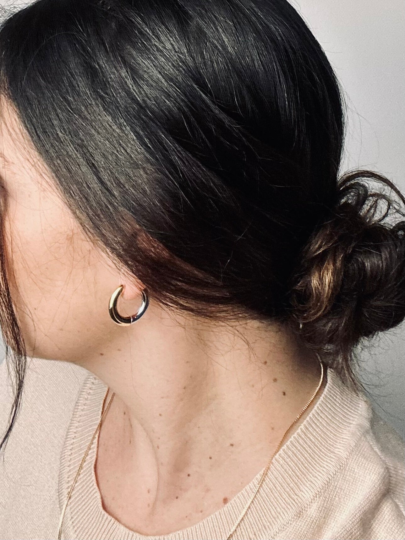 The Lustra two-tone hoop earrings worn by a model, their mix of gold and silver catching the light with effortless elegance. The look embodies quiet confidence and timeless grace — a reminder to shine with poise and self-love.