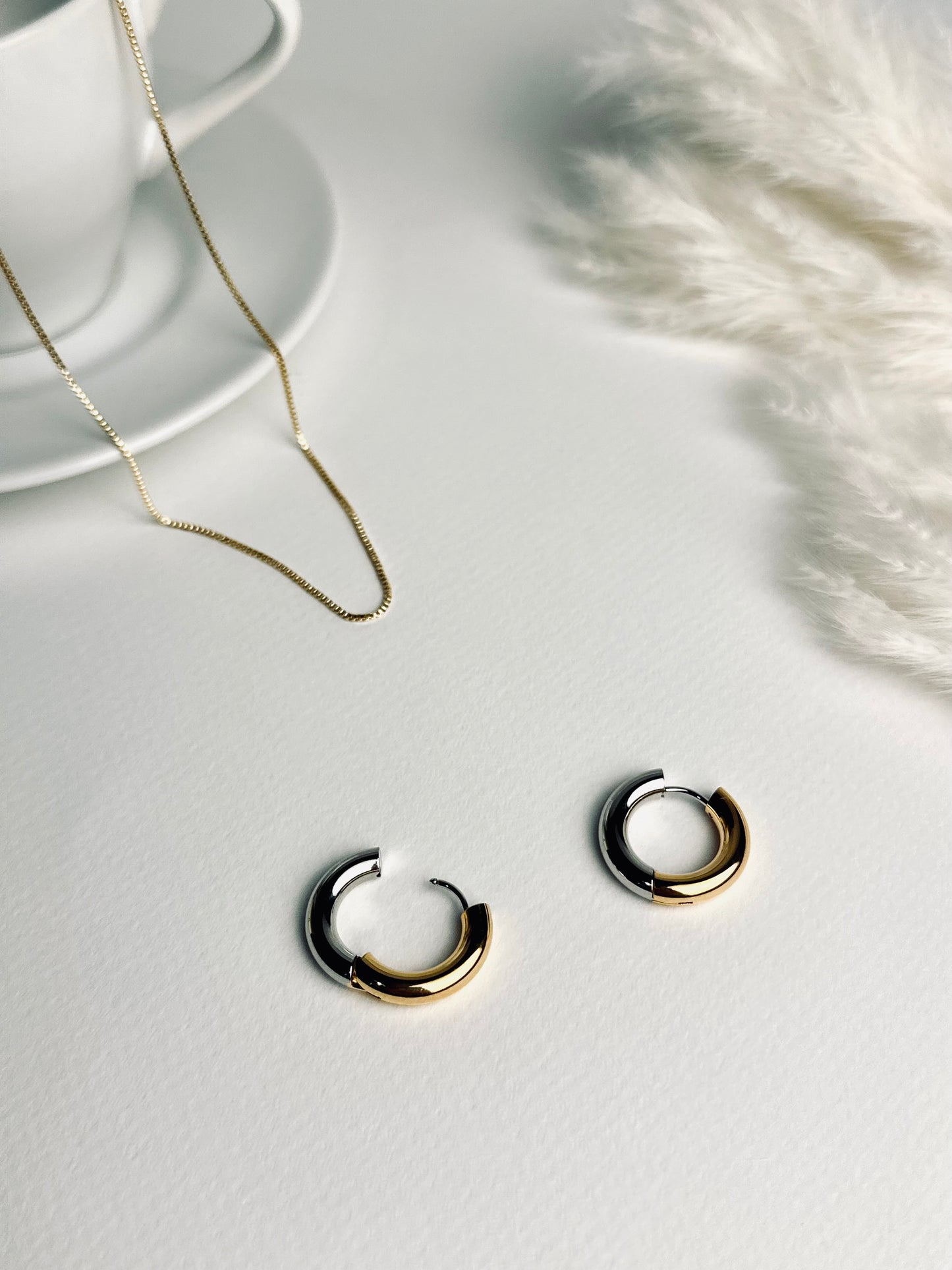 Close-up of the Lustra hoop earrings — elegant two-tone hoops blending warm 18k gold and cool silver tones. Their soft shine symbolizes balance and grace, reflecting the beauty of timeless strength and self-confidence. Part of the “Timeless Grace” collection.