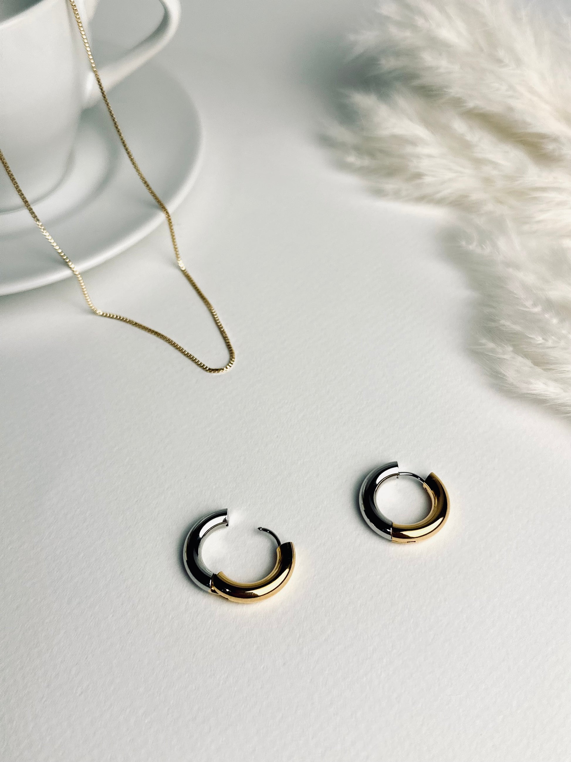 Close-up of the Lustra hoop earrings — elegant two-tone hoops blending warm 18k gold and cool silver tones. Their soft shine symbolizes balance and grace, reflecting the beauty of timeless strength and self-confidence. Part of the “Timeless Grace” collection.
