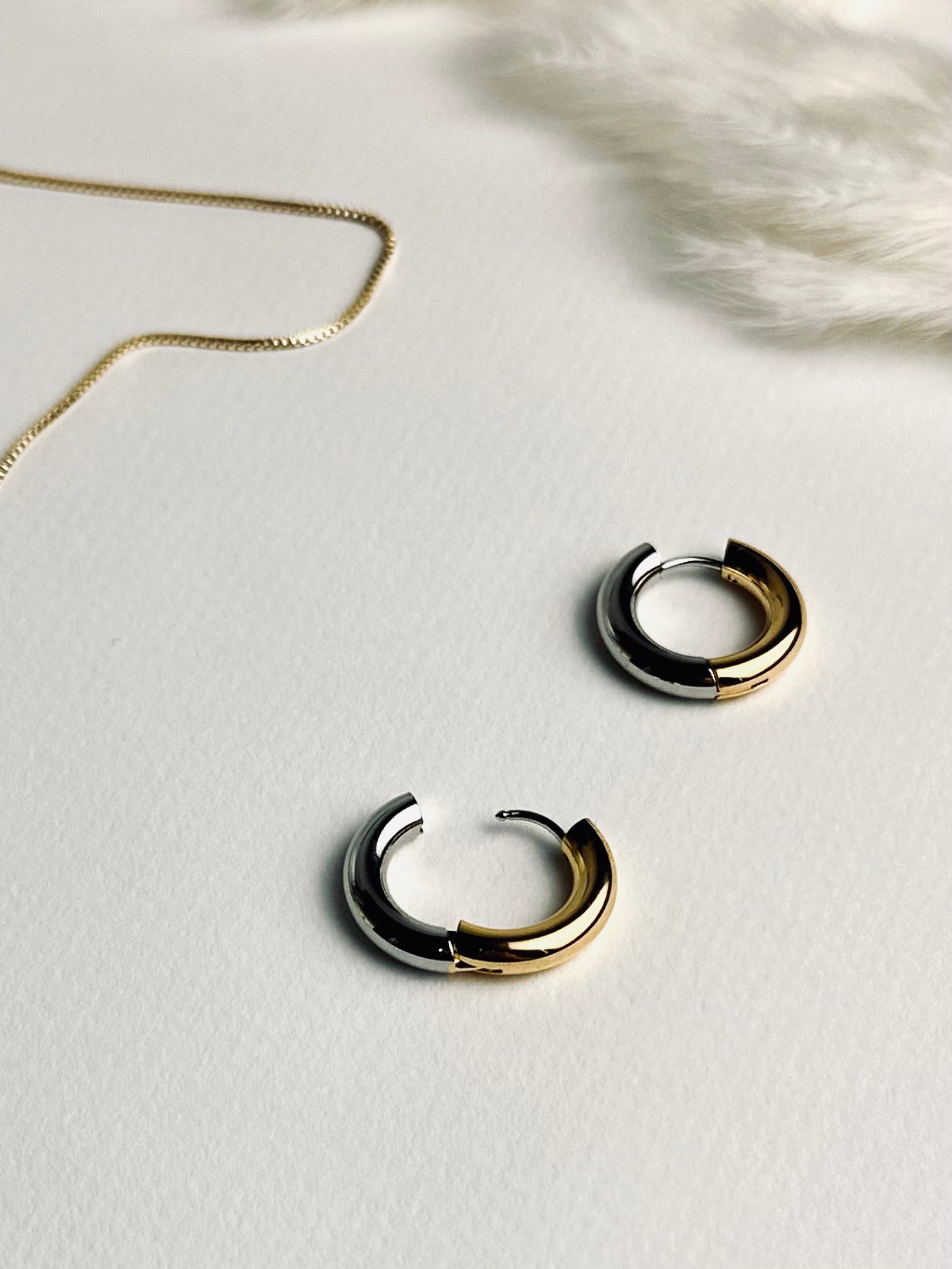Close-up of the Lustra hoop earrings — elegant two-tone hoops blending warm 18k gold and cool silver tones. Their soft shine symbolizes balance and grace, reflecting the beauty of timeless strength and self-confidence. Part of the “Timeless Grace” collection.