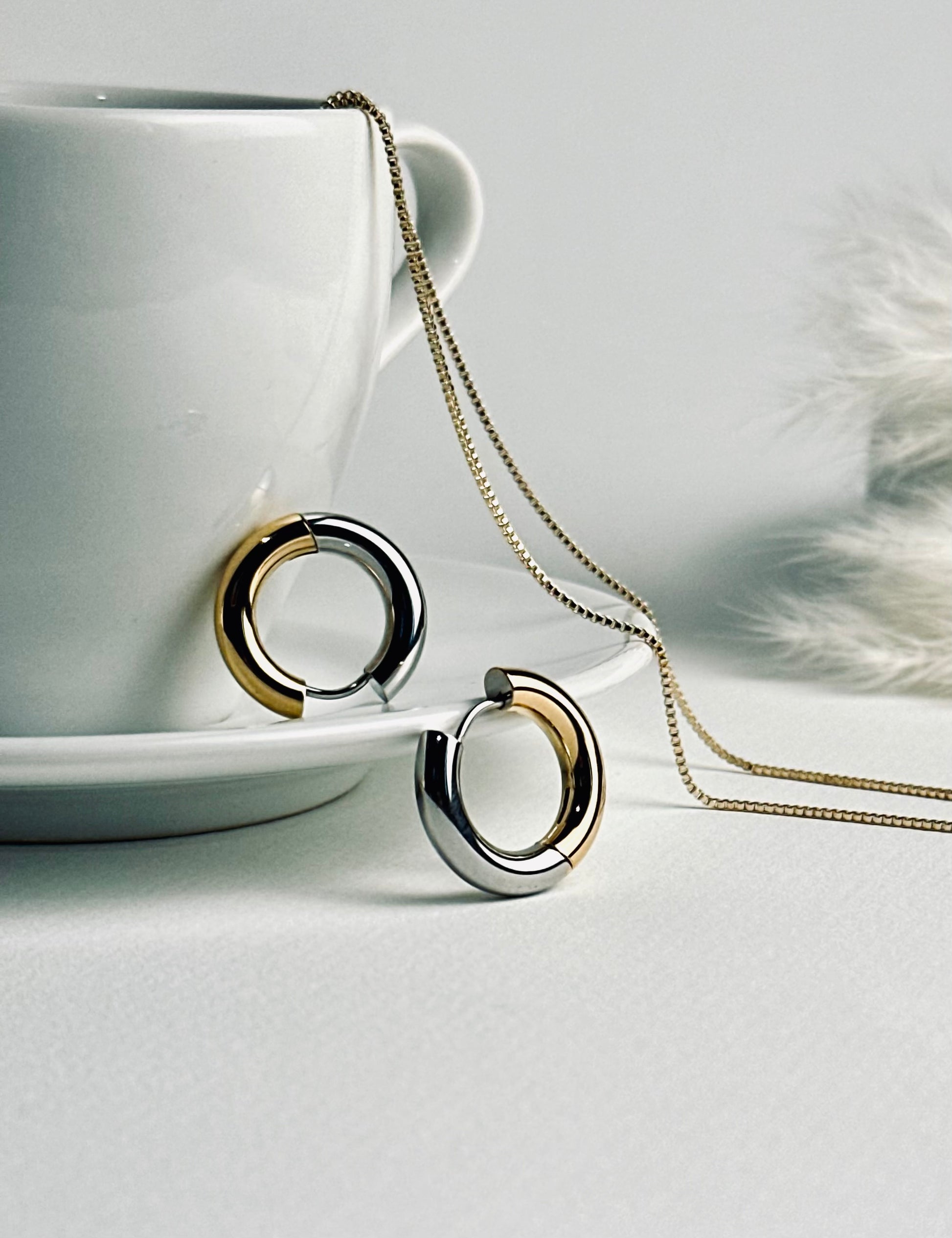 Close-up of the Lustra hoop earrings — elegant two-tone hoops blending warm 18k gold and cool silver tones. Their soft shine symbolizes balance and grace, reflecting the beauty of timeless strength and self-confidence. Part of the “Timeless Grace” collection.