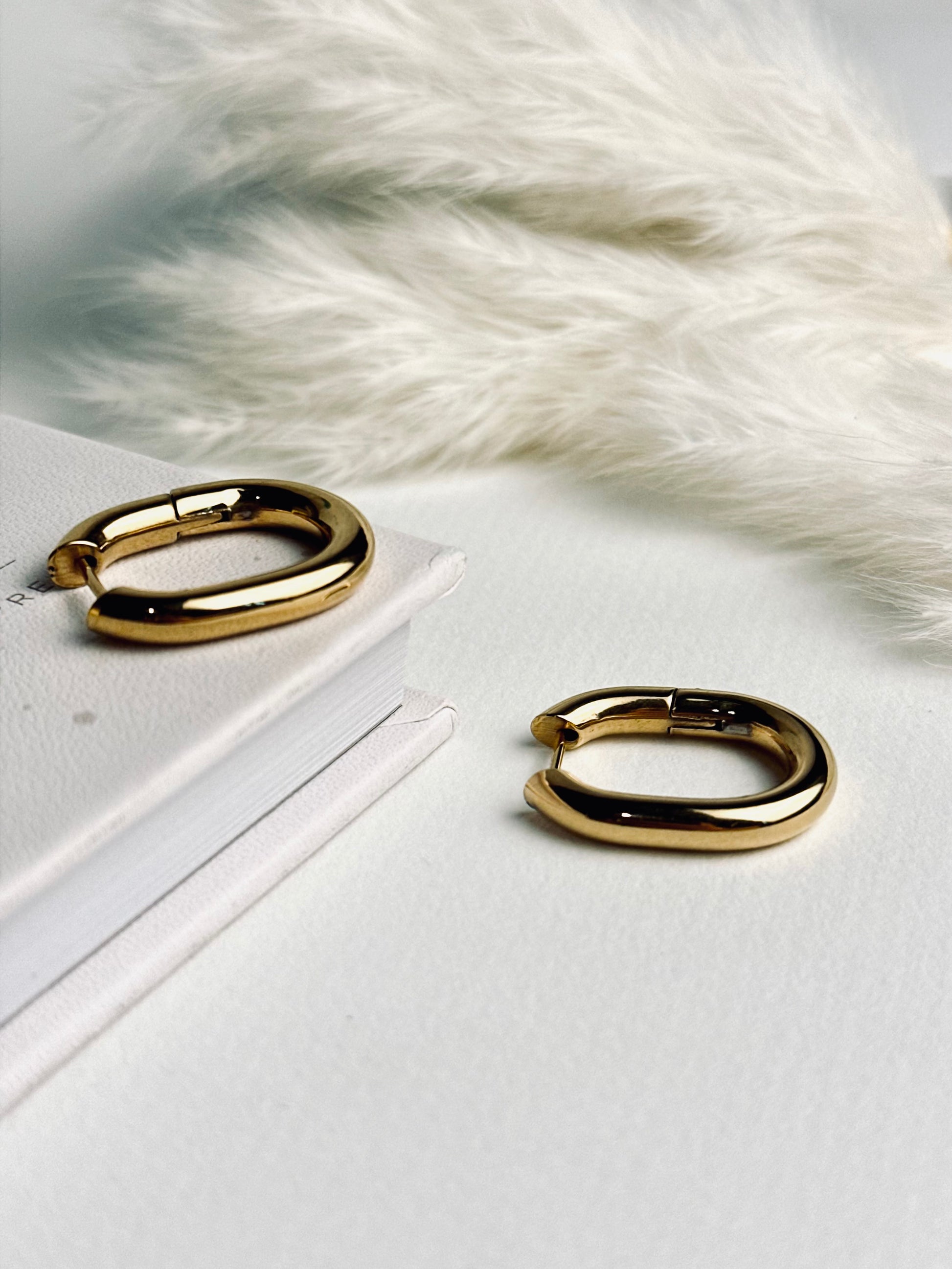 Vera Hoop earrings from the “Timeless Grace” collection displayed flat, showcasing their bold 1-inch 18k gold-plated design. The chunky shape and radiant finish reflect strength and elegance, made to last with hypoallergenic and tarnish-resistant quality.
