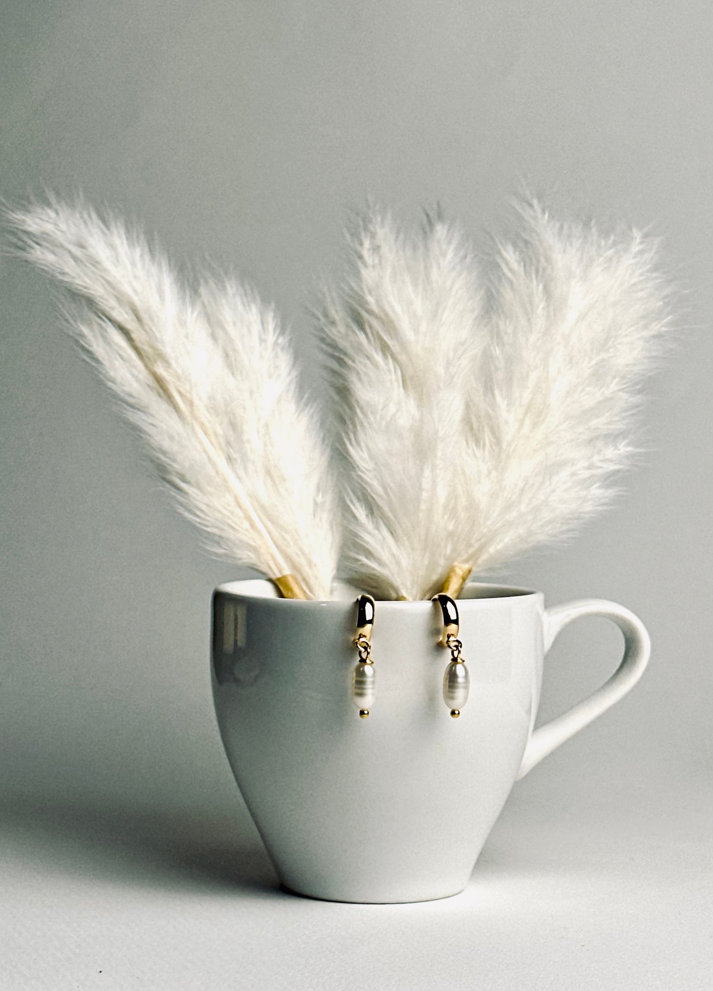 Single pearl displayed on a delicate C-shape earring post, showcasing its minimalist elegance. The soft luster of the pearl conveys timeless beauty, subtle sophistication, and refined grace.