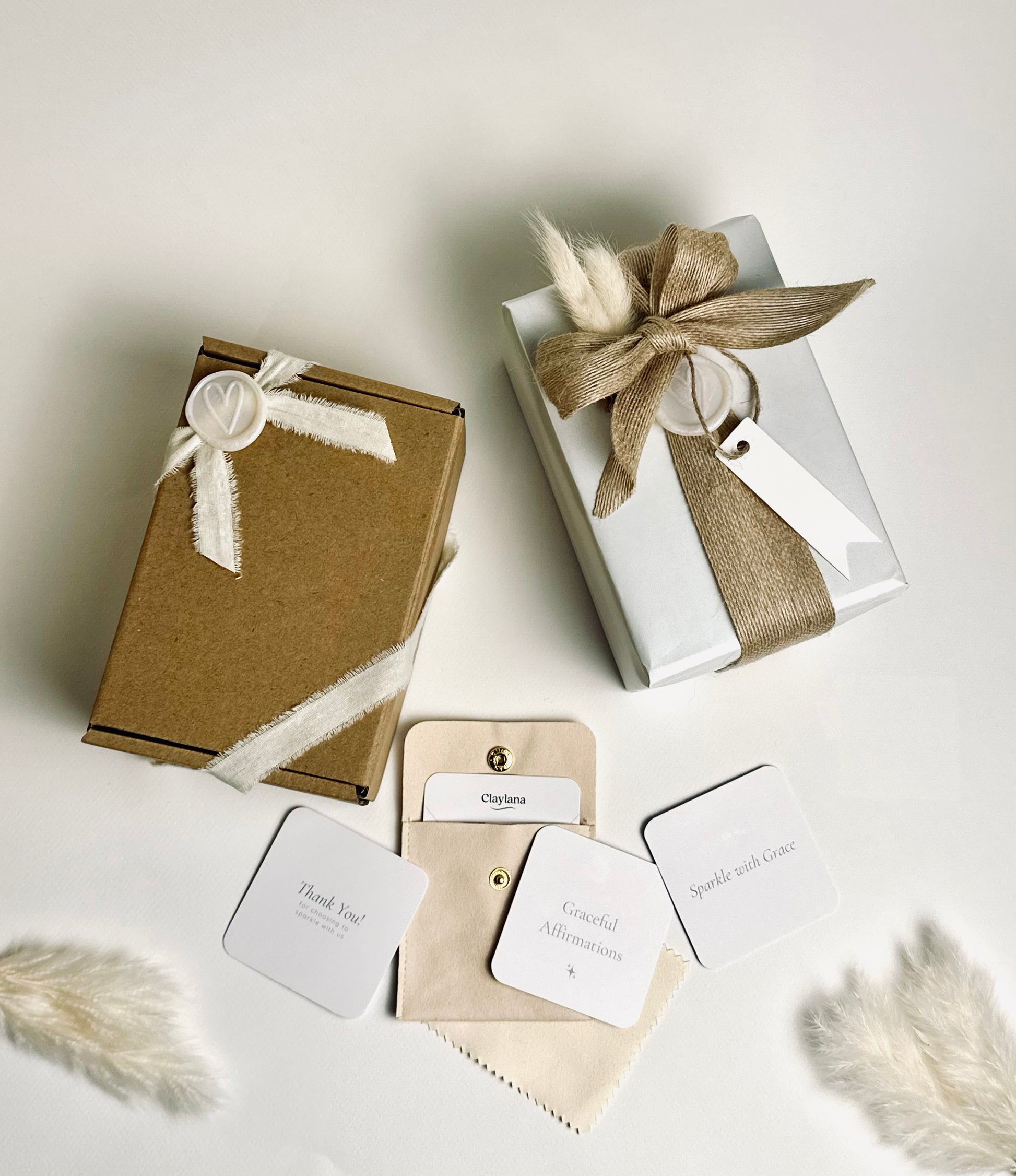 Claylana handmade earrings packaging options: Premium pouch with cloth and affirmation card, Deluxe gift-ready box with care tip card, flat lay on soft teal background.