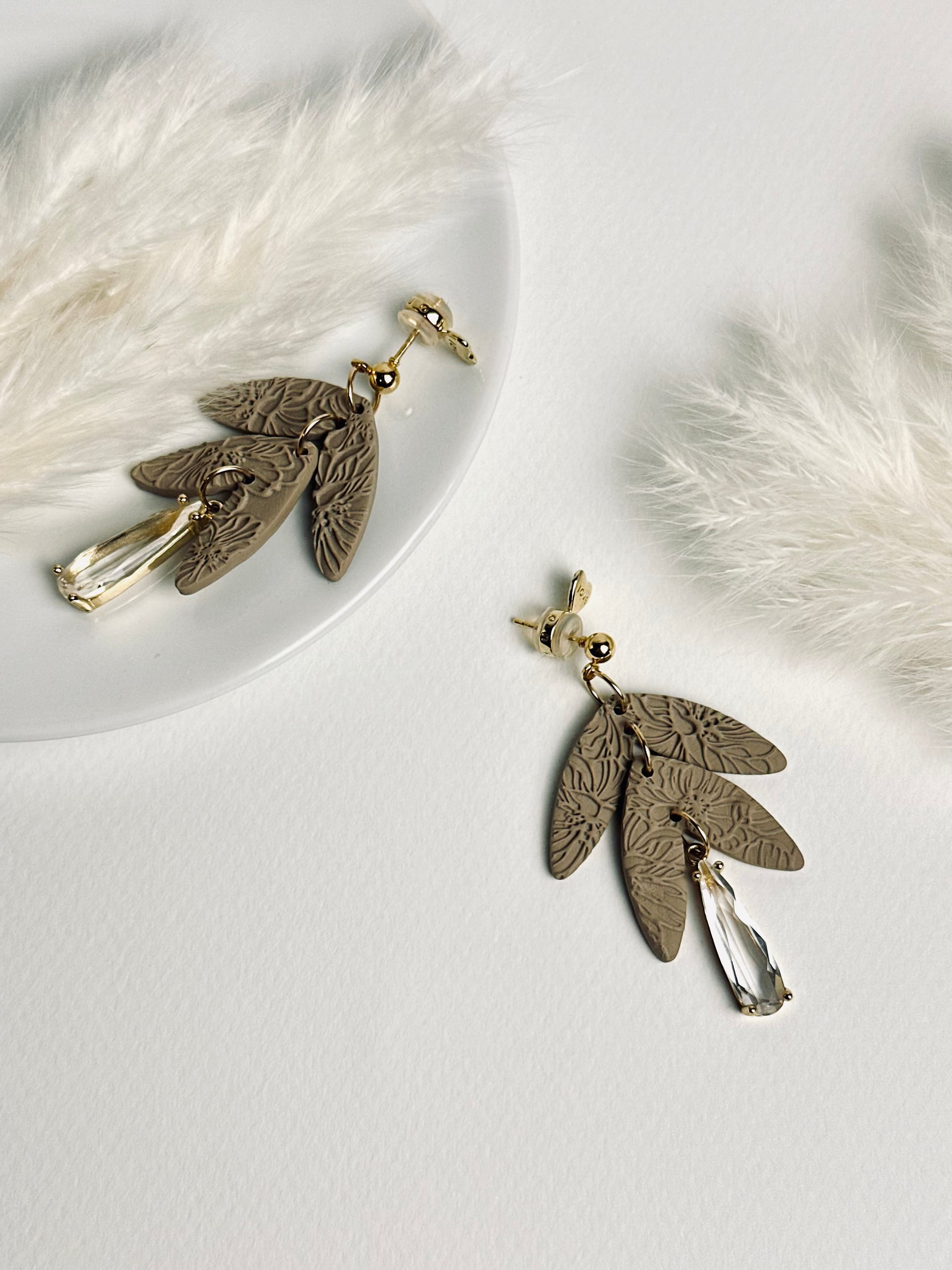 Handmade polymer clay dangle earring with rolled rose texture and a large teardrop crystal accent, elegant and feminine design.