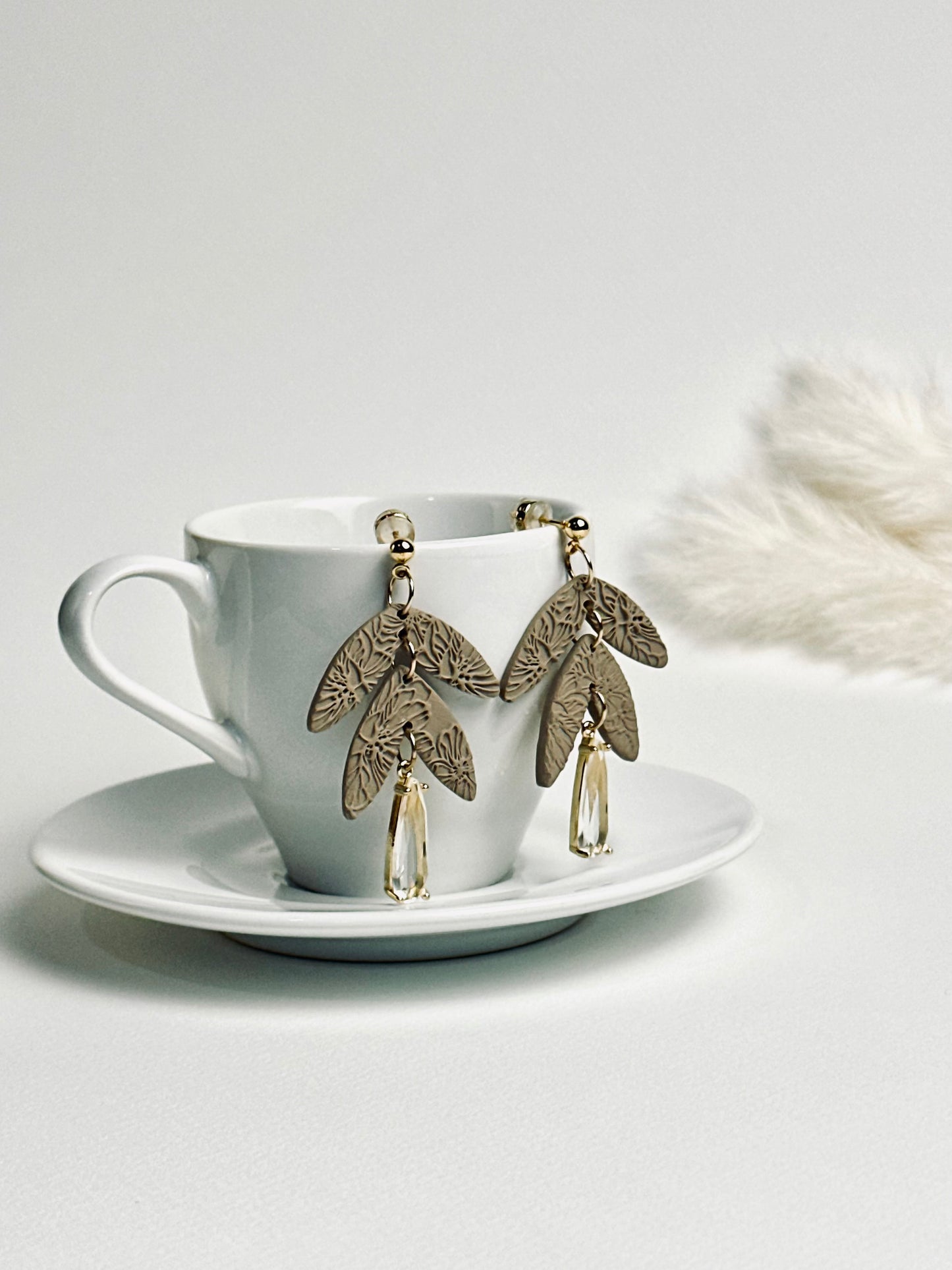 Handmade polymer clay dangle earring with rolled rose texture and a large teardrop crystal accent, elegant and feminine design.