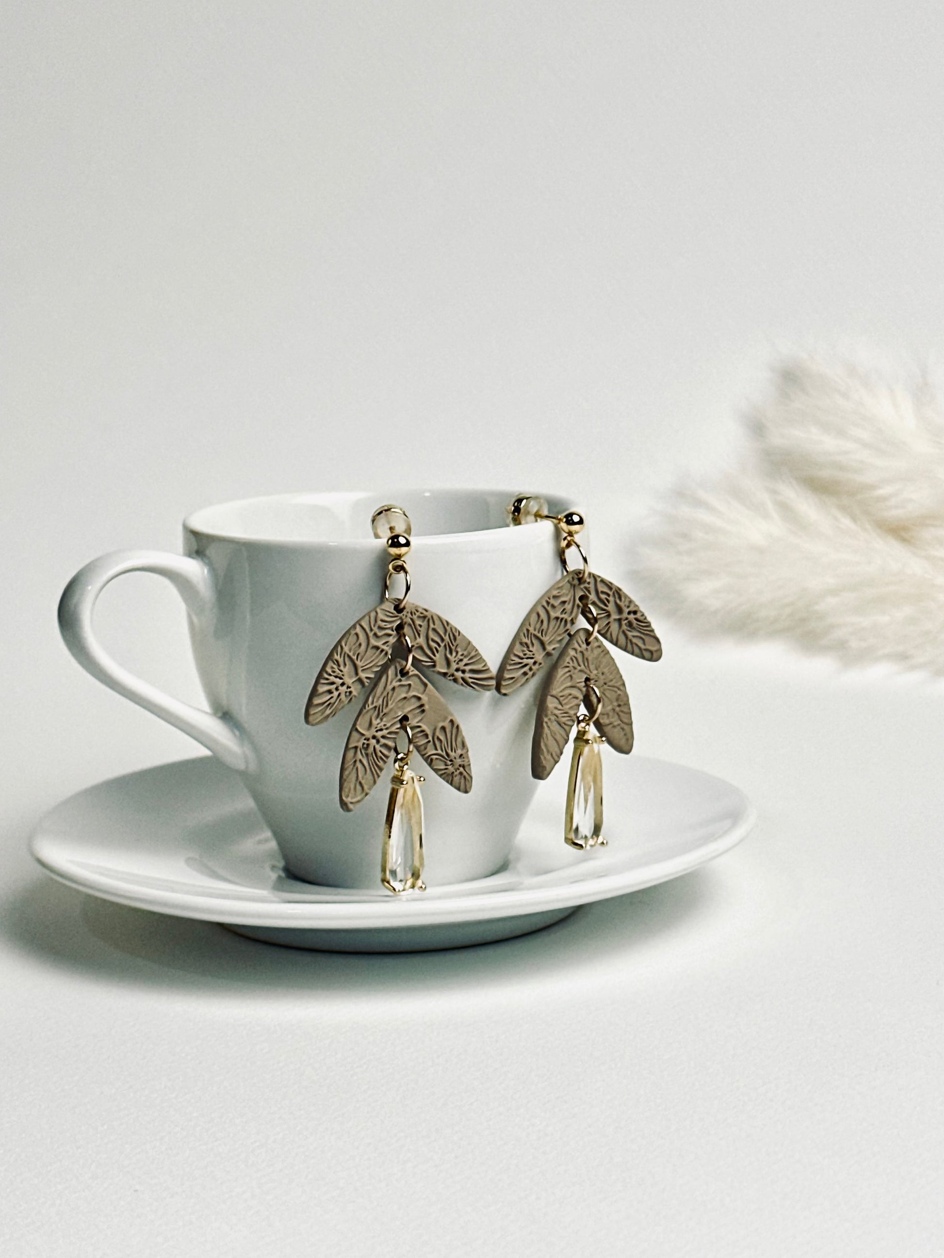 Handmade polymer clay dangle earring with rolled rose texture and a large teardrop crystal accent, elegant and feminine design.